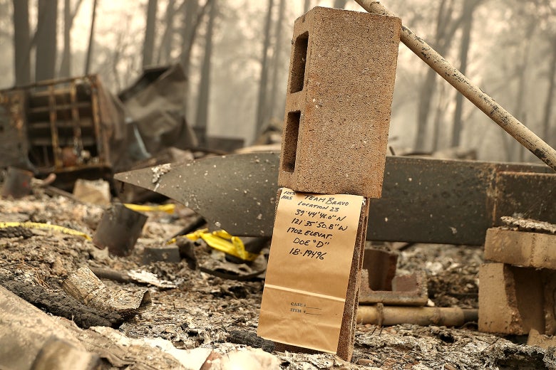 A note is visible where rescuers found a fire victim at a mobile home park that was destroyed by the Camp Fire on Nov. 14 in Paradise, California. The note, written on a brown paper bag, says "Team Bravo, Location 23, 39 44' 46.0" N, 121 35' 50.8" W, 1702 Elevat., Doe "D", 18-19496"